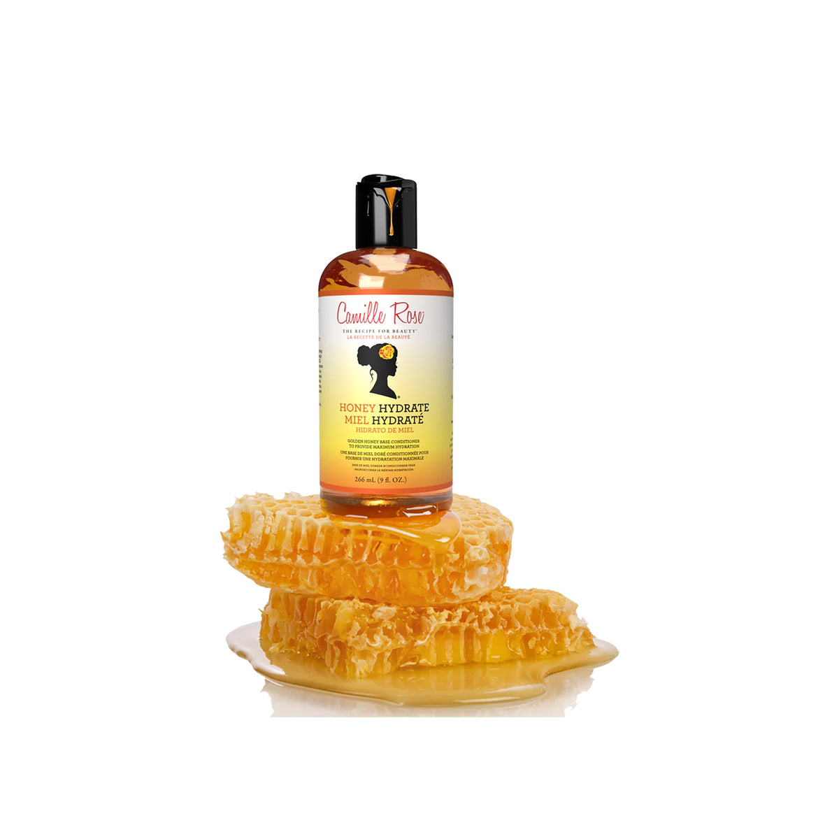 Gylden flaske med Camille Rose Honey Hydrate Leave-In Conditioner på en hvid baggrund, omgivet af honningkager.